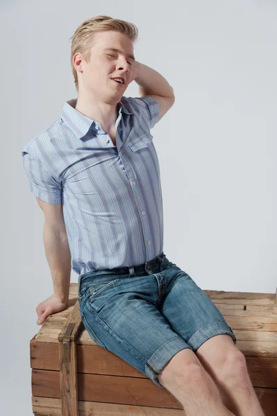 Young man sits on wooden box — Stock Photo, Image