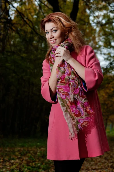 Красивая женщина в розовом пальто прогулки в парке — стоковое фото