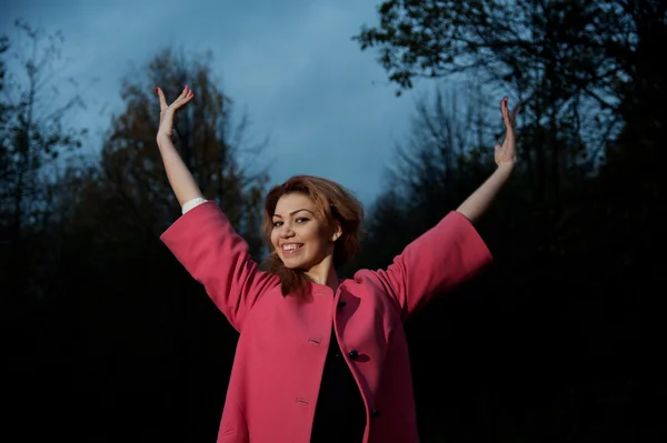 Mooie vrouw in roze vacht wandelingen in het park — Stockfoto