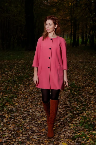 Bella donna in cappotto rosa passeggiate nel parco — Foto Stock
