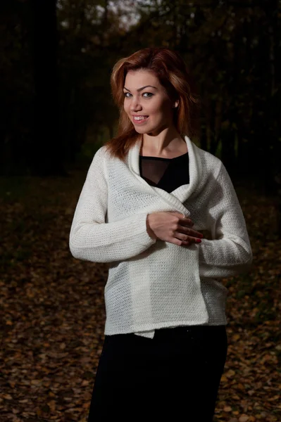 Schöne Frau im weißen Pullover spaziert durch den Park — Stockfoto