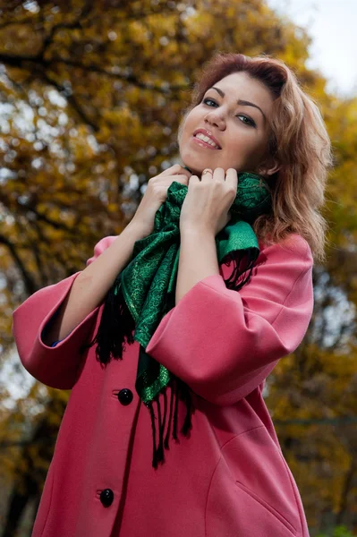 Vacker kvinna i rosa kappa promenader i parken — Stockfoto