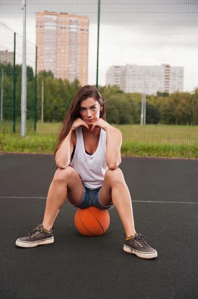 Basketbol üzerinde oturan kadın — Stok fotoğraf