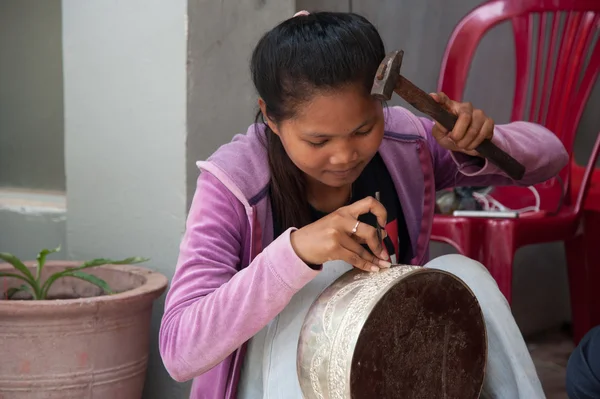 Asian girl makes a figure on a silver bowl — Stock Photo, Image