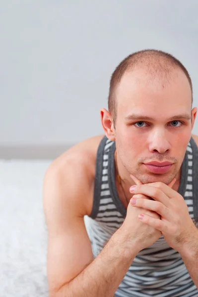 Mann im T-Shirt sitzt auf Bett — Stockfoto