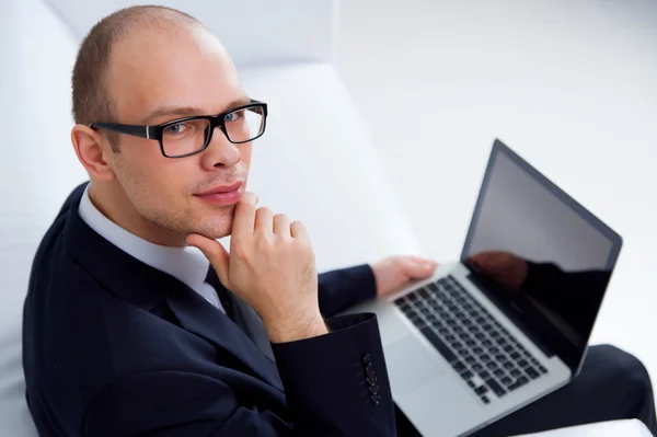 Улыбающийся бизнесмен сидит с ноутбуком — стоковое фото