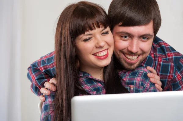 Молодая смеющаяся пара использует ноутбук дома — стоковое фото