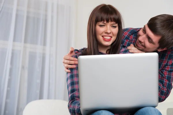 Портрет молодой улыбающейся пары с помощью ноутбука, сидящей за h — стоковое фото