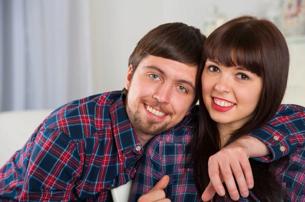 Relajante joven pareja sentada en el sofá en el interior de casa — Foto de Stock