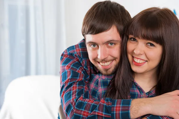 Portrait of young love couple sitting on couch and smiling — Stock Photo, Image