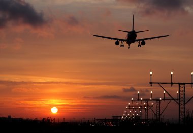 Plane landing in a sunset clipart