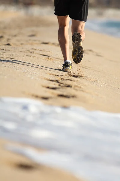 ビーチの砂の上を実行している男の足 — ストック写真