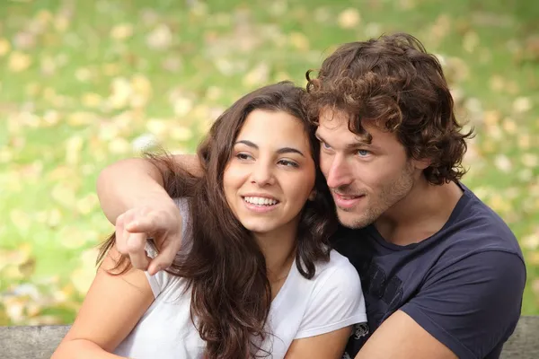 Pareja en un parque mirando donde el hombre señala — Foto de Stock