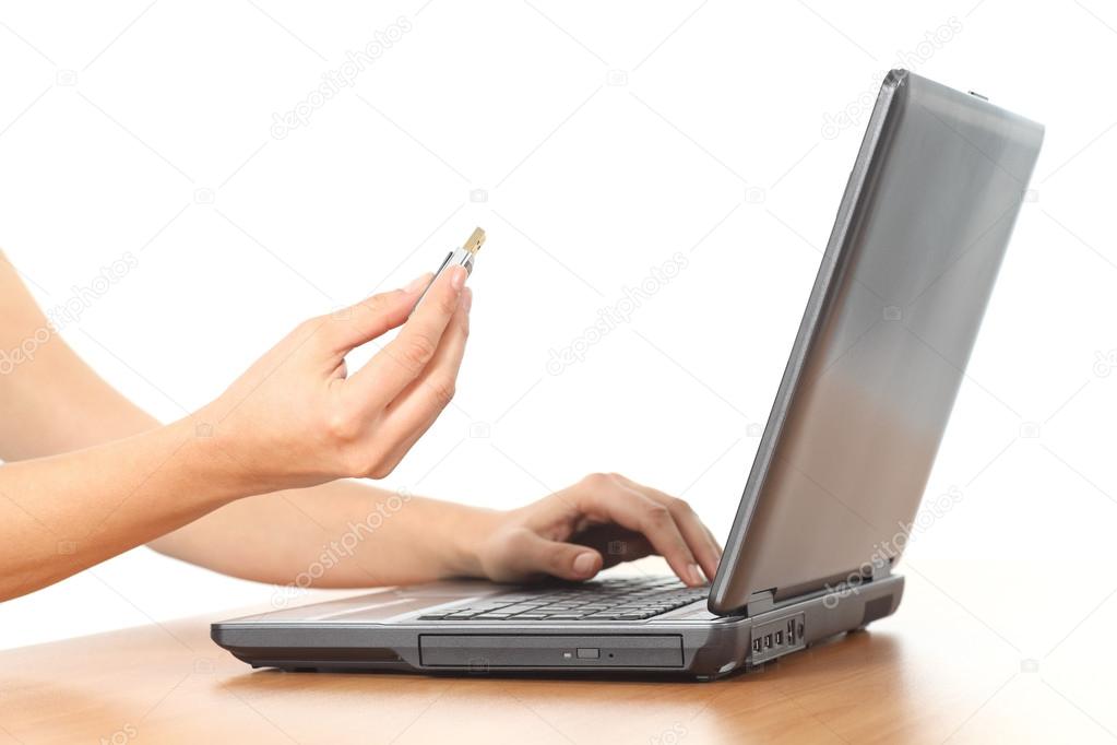 Beautiful woman hands on a laptop with a pen drive