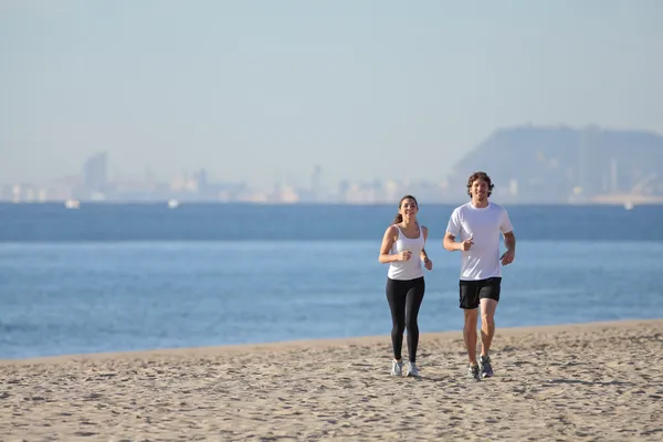 Mujer y hombre corriendo en la playa hacia el mar —  Fotos de Stock