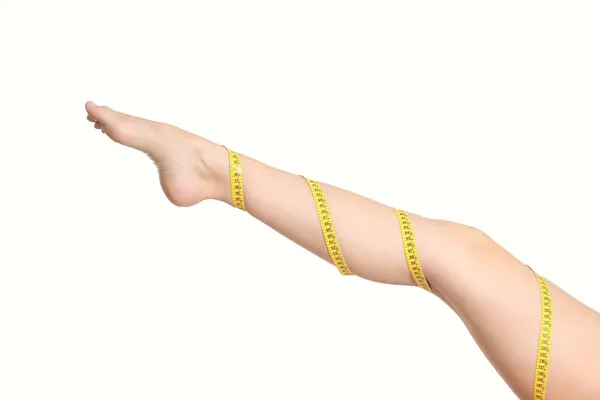 Beautiful woman leg with a coiled measure tape — Stock Photo, Image