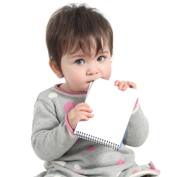 Baby innehav och biter en tom anteckningsbok — Stockfoto
