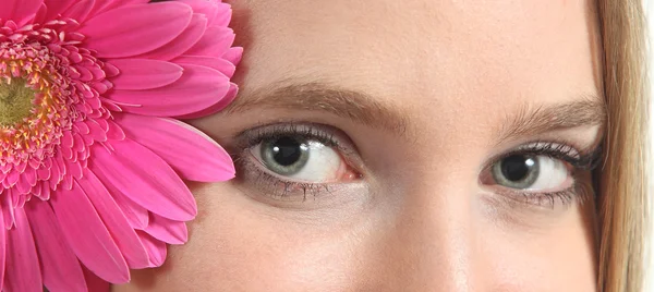 Retrato de um belo olhos azuis de uma mulher com uma flor rosa — Fotografia de Stock