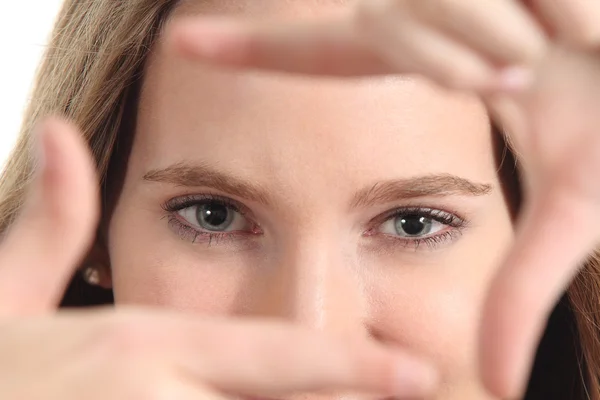 Vacker kvinna framing hennes blå ögon med fingrarna — Stockfoto