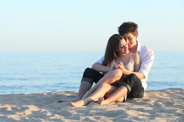 情侣拥抱坐在海边的沙滩上 — 图库照片