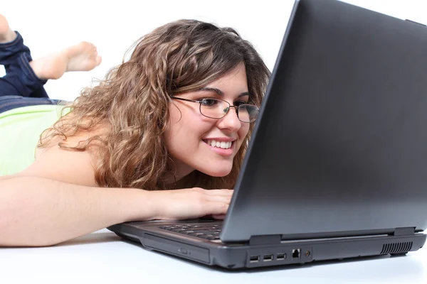 Beautiful woman lying and browsing in a laptop — Stock Photo, Image