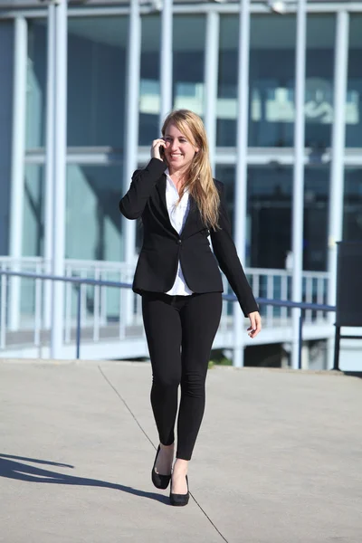 Heureuse femme d'affaires sur le téléphone portable marchant dans la rue — Photo