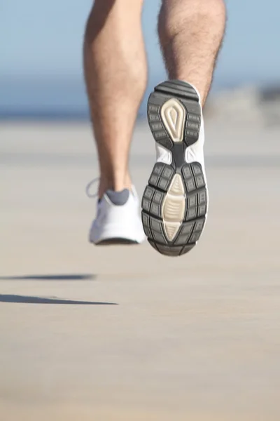 Närbild av ett ofokuserat man benen körs på betongen av havet — Stockfoto