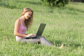 Gyönyörű tizenéves lány egy laptop a fűben