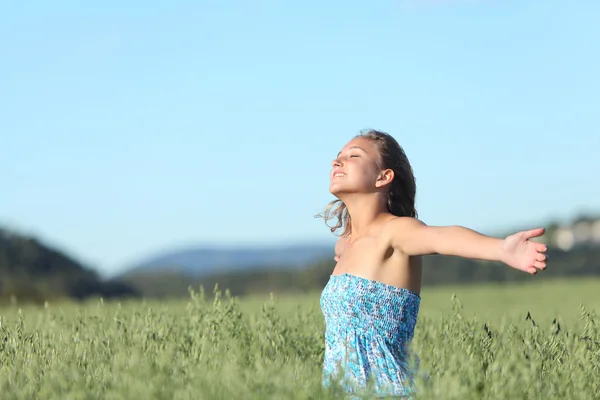 Mooie vrouw ademhaling gelukkig met opgeheven armen in een weide groen haver — Stockfoto