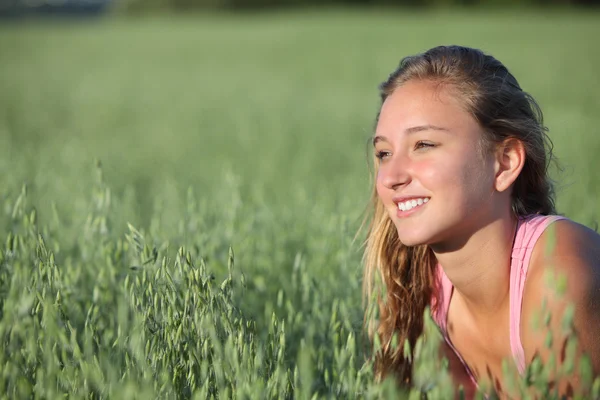 Yulaf çayırda gülümseyen bir genç kızın yakın çekim — Stok fotoğraf