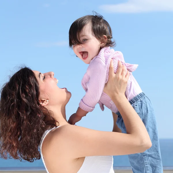 Pretty mum laughing and raising her daughter — Stock Photo, Image