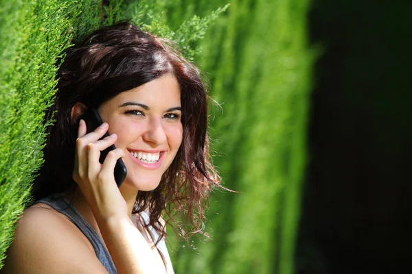 Atrakcyjna kobieta uśmiechając się na telefon w parku — Zdjęcie stockowe