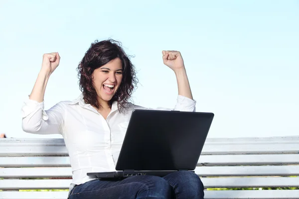 Euforisch zakenvrouw met een laptop zittend op een bankje — Stockfoto