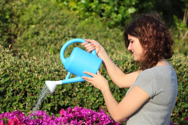 Bella donna che annaffia fiori con un annaffiatoio — Foto Stock