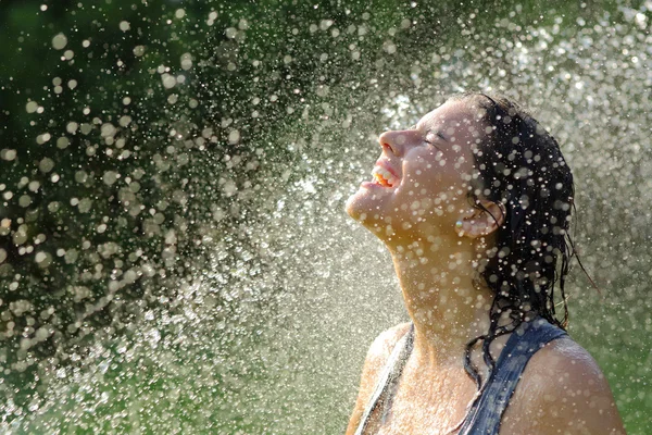 Красивая женщина наслаждается под струей воды — стоковое фото