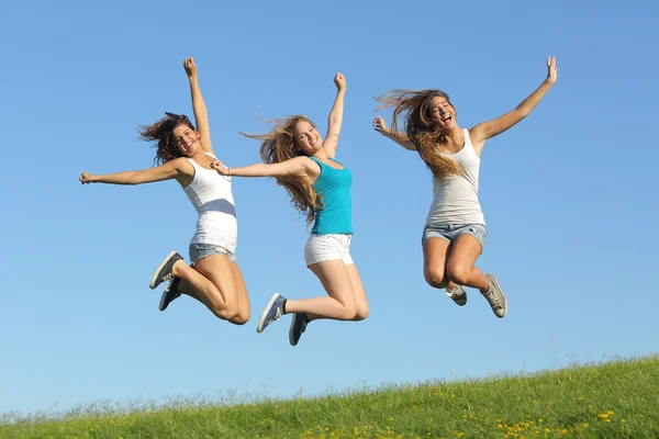 Group of three teenager girls jumping on the grass — Stock Photo, Image