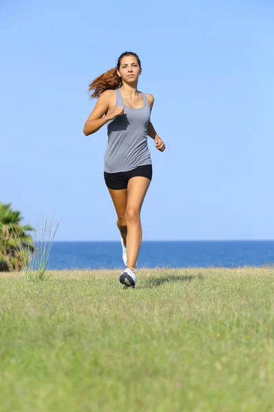 Front view of a beautiful woman running on the grass Stock Picture