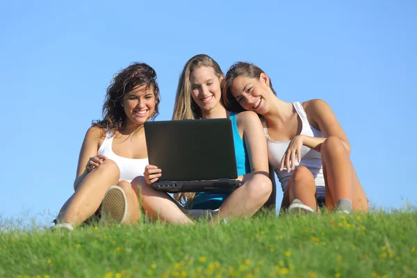 Grupo de tres chicas adolescentes riendo mientras miran el portátil al aire libre — Foto de Stock