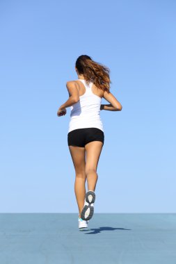 Back view of a fitness woman running on blue