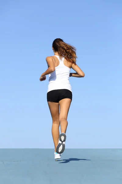 Back view of a fitness woman running on blue — Stock Photo, Image