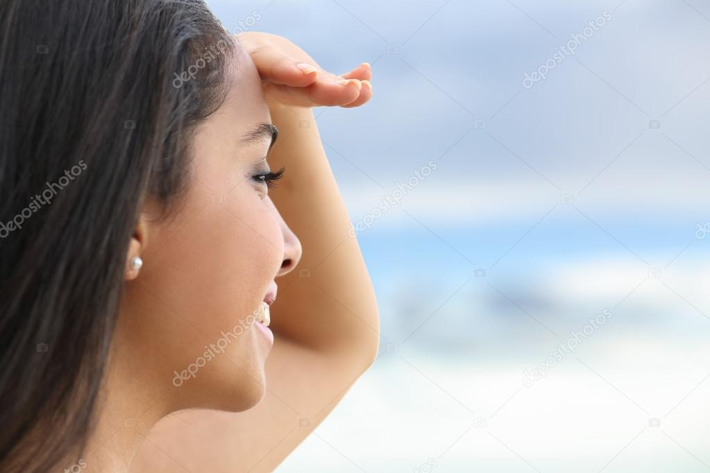 Close up of a beautiful woman looking at the horizon with a hand in forehead
