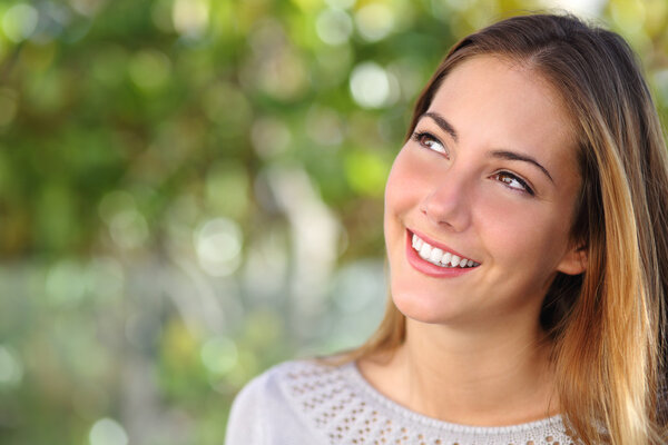 Beautiful woman smiling with a perfect teeth and looking above