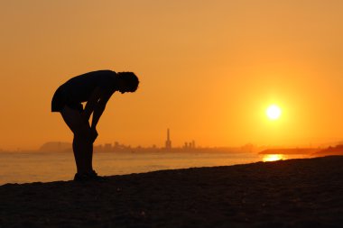 Silhouette of an tired sportsman at sunset clipart