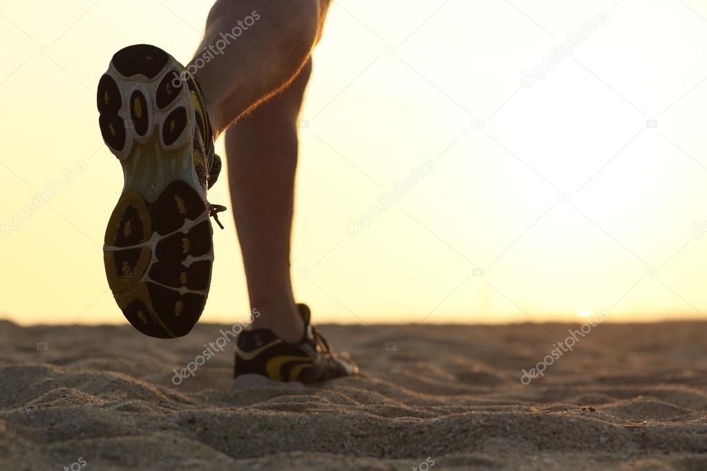 Legs and shoes of a man running at sunset