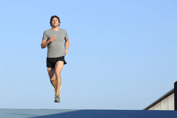 Jogger running towards camera on blue — Stock Photo, Image