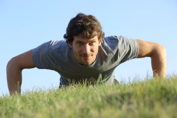 Close up of a man doing pushups on the grass — Stock Photo, Image