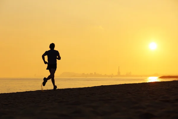在日落时在沙滩上跑步的慢跑者剪影 — 图库照片