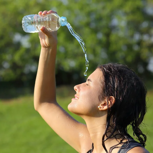 Belle femme se jetant de l'eau d'une bouteille en plastique — Photo