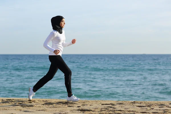 Arabo saudita corridore donna in esecuzione sulla spiaggia — Foto Stock