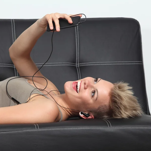 집에서 소파에 여자는 smartphone에서 음악을 듣고 — 스톡 사진